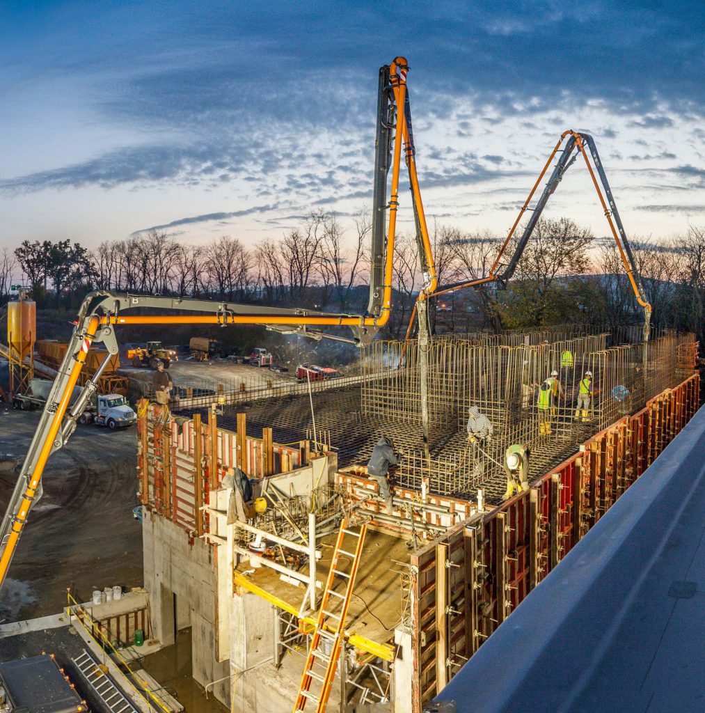 construction site at dusk with cranes and design-build contractors