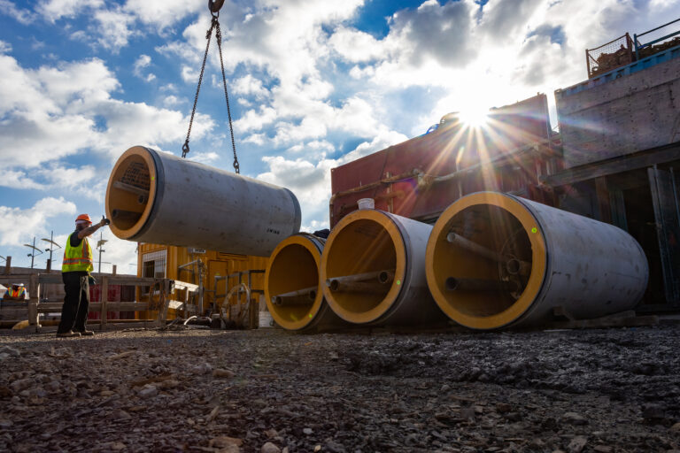 Ewing Fabricators lowering concrete pipe onto jobsite