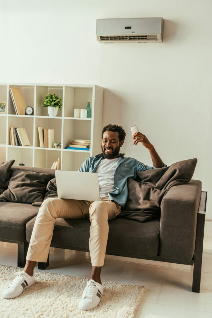 man sitting on couch with remote for ac designed by blocpower