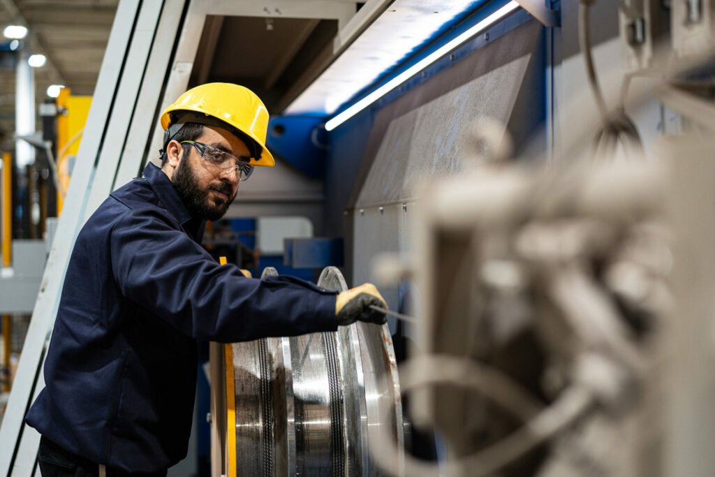 Numesh employee in manufacturing plant guiding steel mesh wire into machine