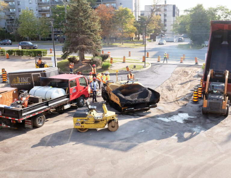 Construction site with workers standing around vehicles and equipment,