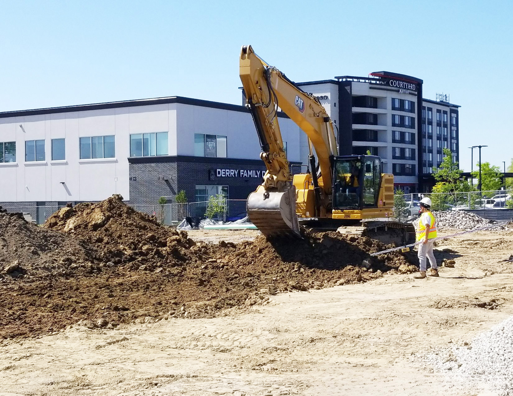 Construction site with excavator flattening new soil.