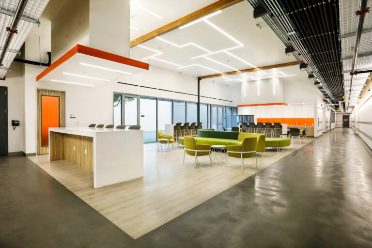 An image of a newly constructed office space with high ceilings, vibrant furniture and cement floors.