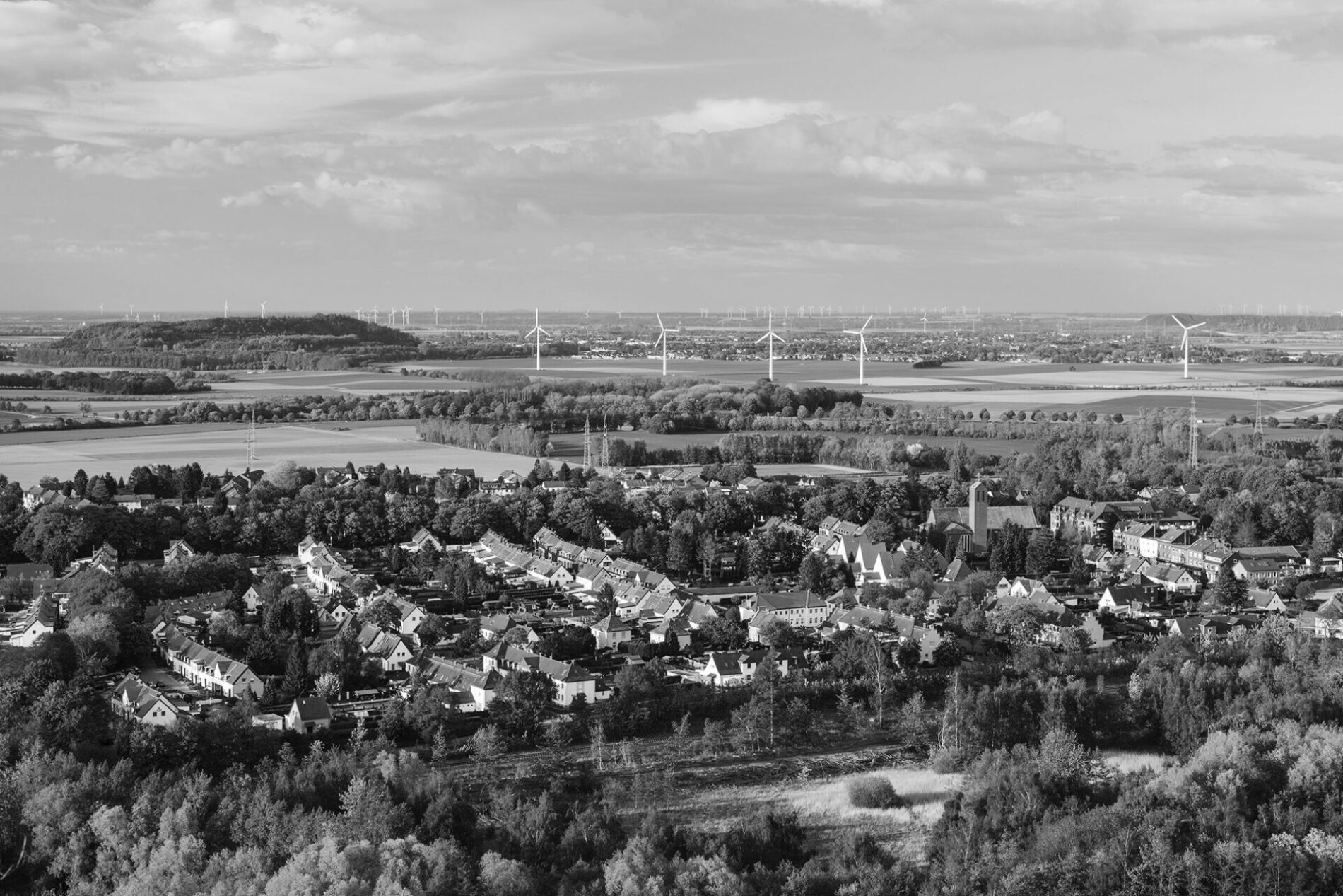 Flat west German landscape near Aachen and Herzogenrath with lots of wind turbines and a village in the foreground.