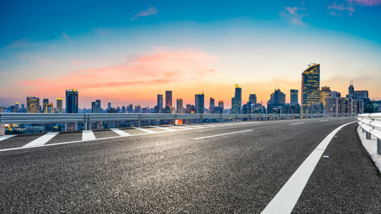 Empty asphalt road and city skyline with buildings at sunset in Shanghai.