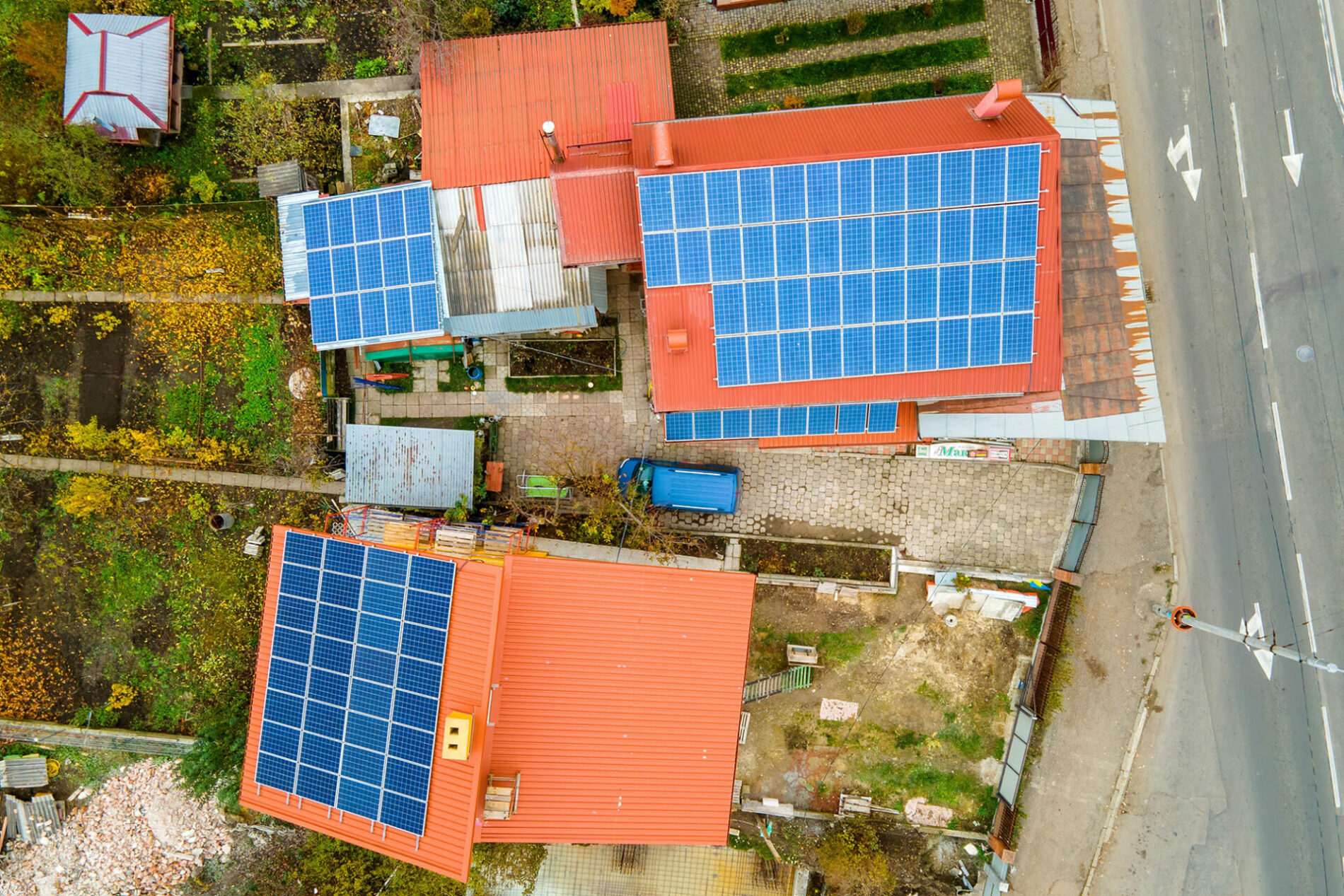 Aerial view of residential houses with rooftops covered with solar photovoltaic panels in suburban rural area