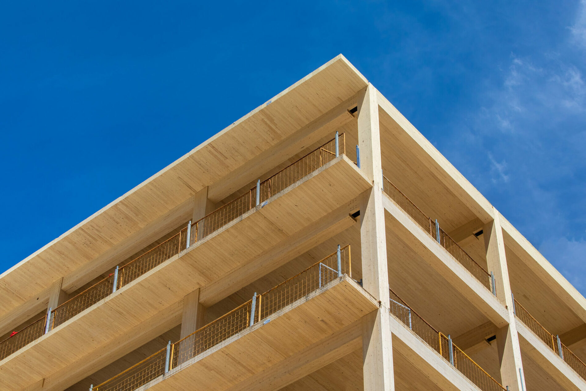 Looking up at the vertical supports, balconies and interior ceiling of a engineered timber multi story green, sustainable residential high rise apartment building construction project