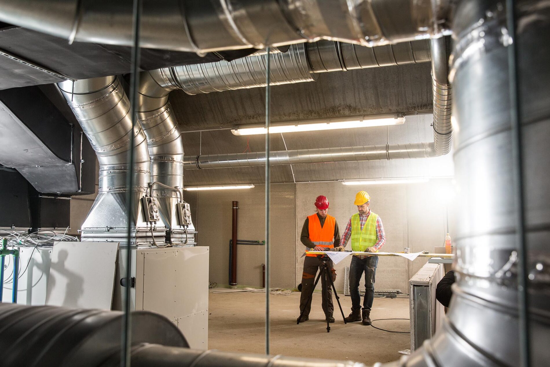 Workers making final touches to HVAC system. HVAC system stands for heating, ventilation and air conditioning technology. Team work, HVAC, indoor environmental comfort concept photo.